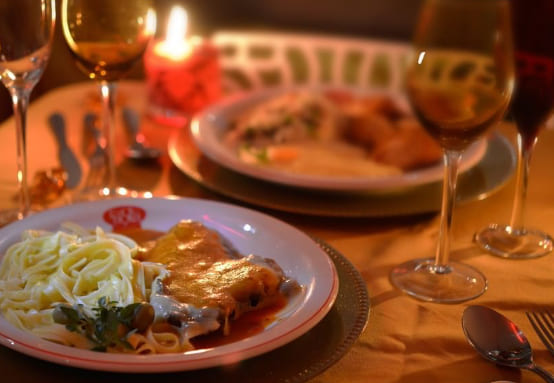 dois pratos de comida em uma mesa com vela e taças de vinho
